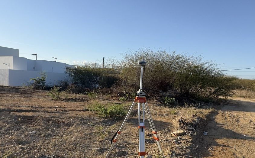 Receptor GNSS RTK sobre tripé durante levantamento topográfico de terreno em Cajazeiras – PB
